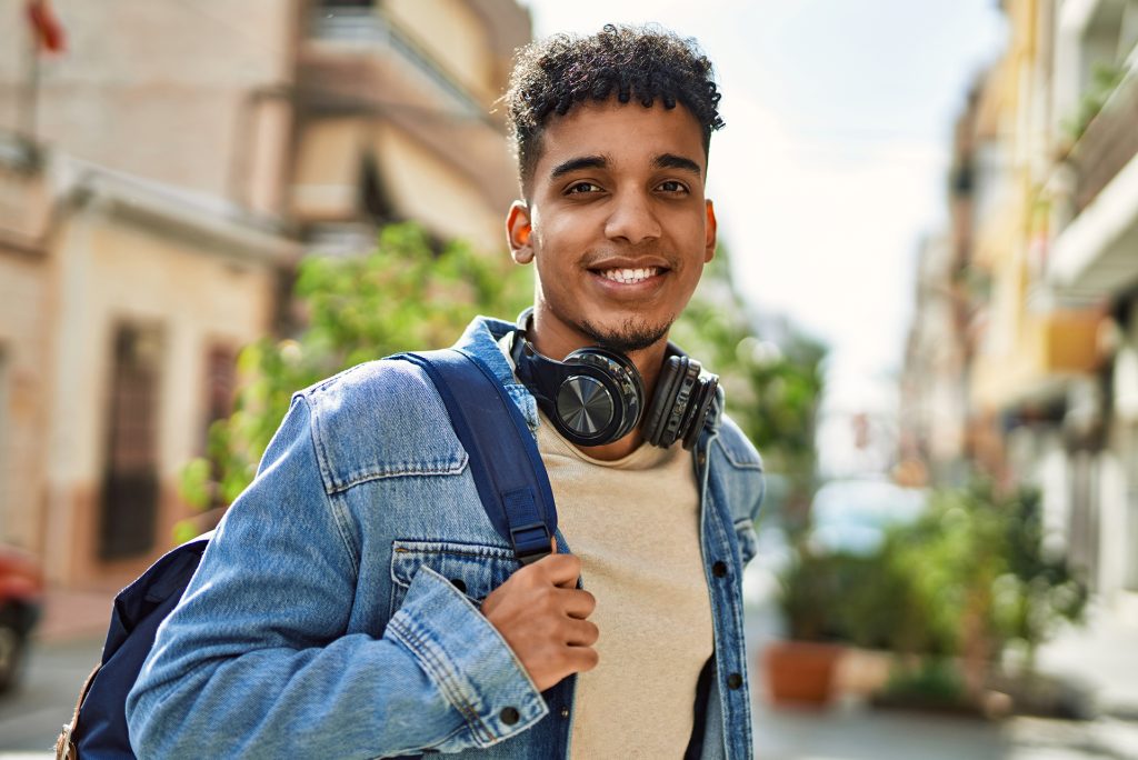 Jongevolwassene, tiener, jongen met koptelefoon en rugzak